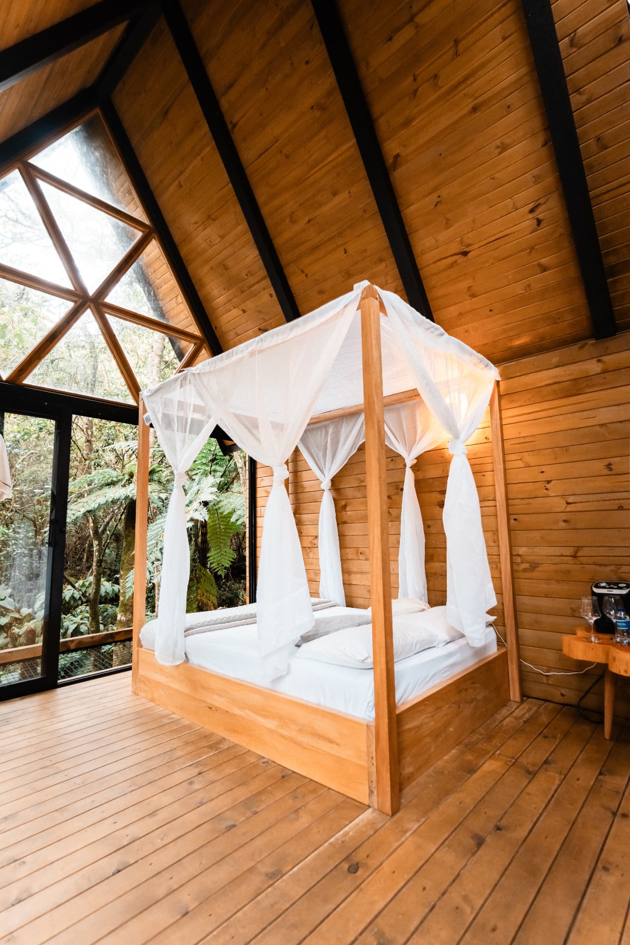 Cama con dosel blanco y ventana triangular en Madriguera